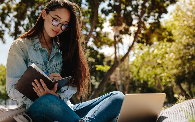 Foto studente che valuta offerte formative al computer, con appunti e libri